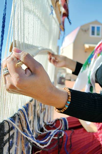 Navajo Times | Holly JamesTasheena Littleben mindfully adjusts the batten and shuttle stick. Littleben explains weavers use their hands through every process.